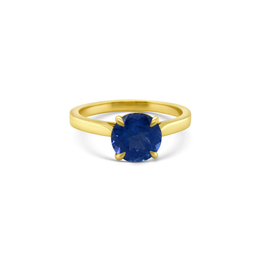 A round solitaire tanzanite ring featuring a brilliant gemstone, perfect for elegant occasions, showcasing timeless beauty, capturing attention with its captivating hue, embodying sophistication and grace, ideal for adding a touch of luxury to any ensemble.