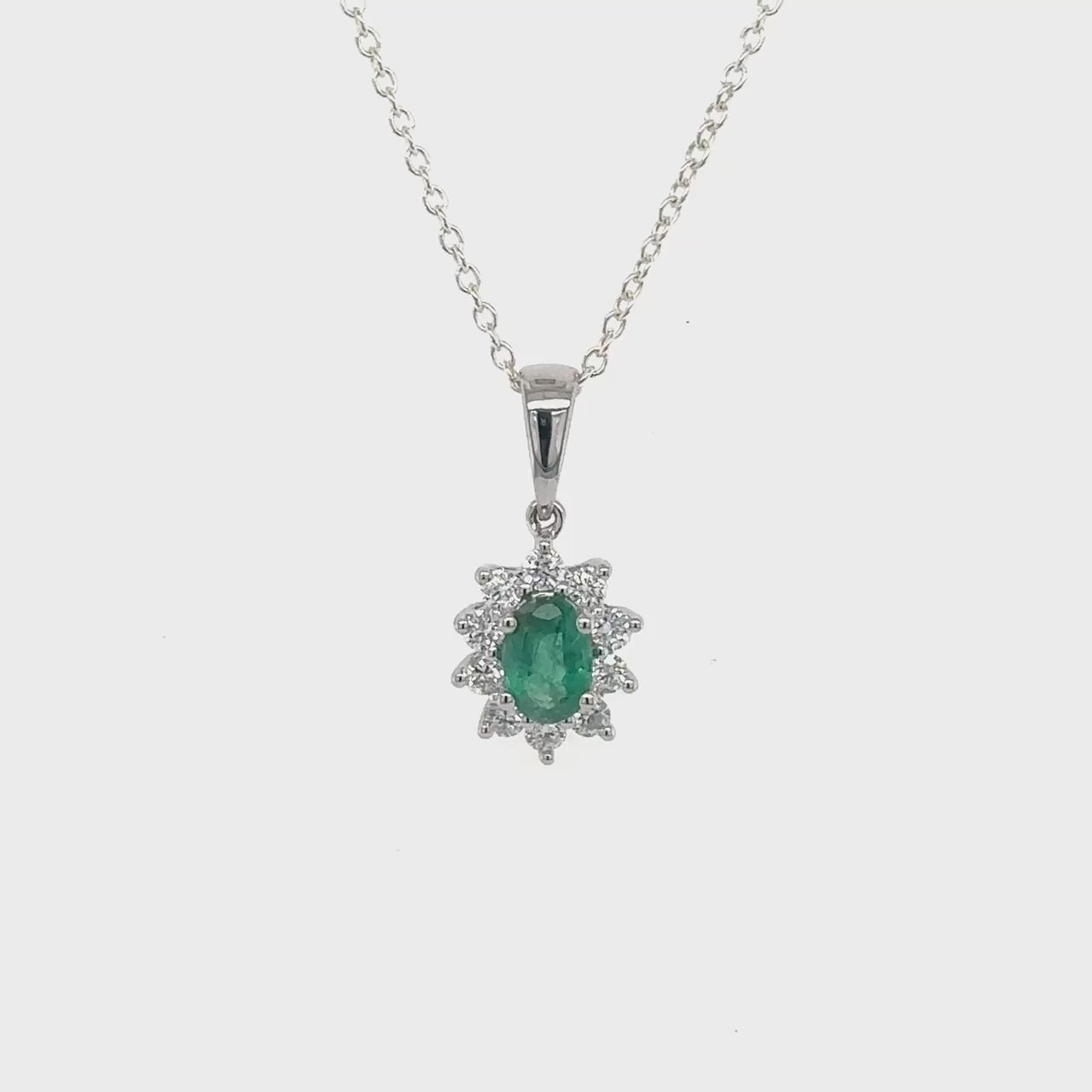  Oval emerald pendant, halo diamond pendant, jewelry with emerald gemstone, necklace with diamond halo, luxurious emerald and diamond accessory, elegant pendant with oval emerald and diamond halo, emerald and diamond pendant for formal occasions.