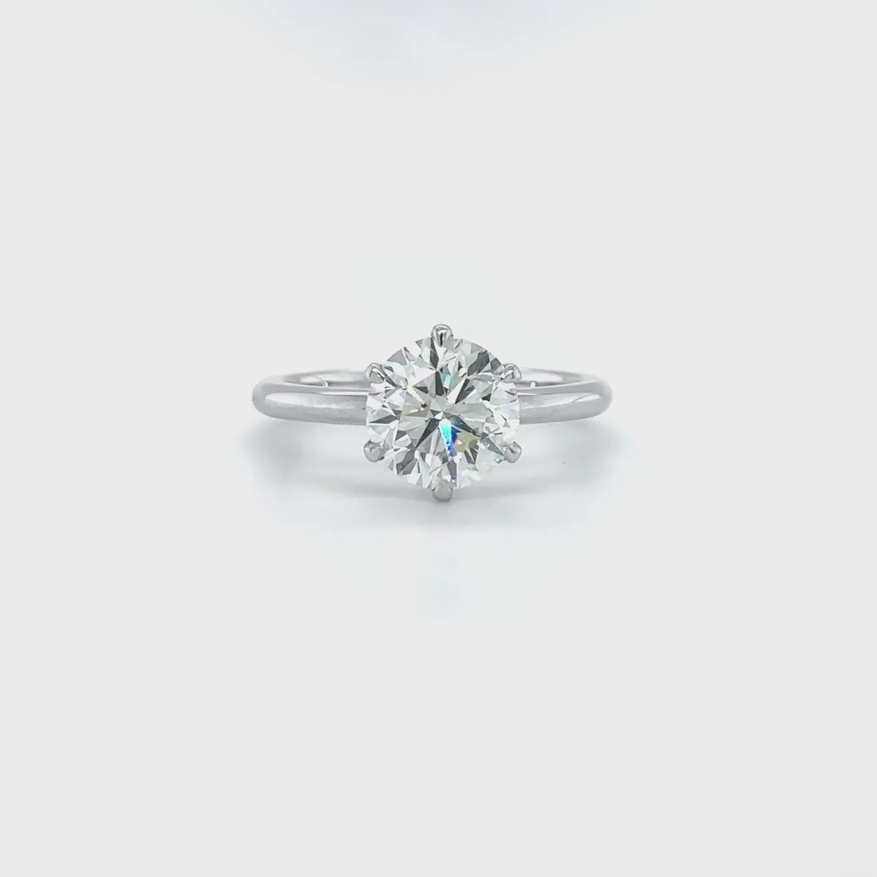 A, round, brilliant, solitaire, diamond, ring, with, a, sparkling, center, stone, set, in, a, prong, setting, on, a, polished, metal, band.